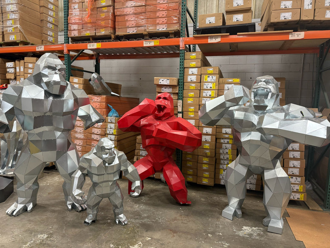 Five low poly metal King Kong sculptures batch-produced in a warehouse, four in galvanized steel and one painted red