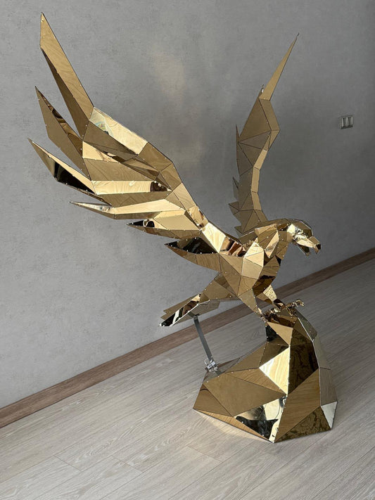 Welded low poly metal eagle with spread wings in a polished gold finish, displayed indoors