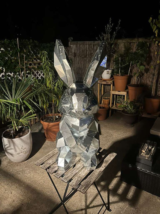 Riveted low poly metal rabbit sculpture on a garden table at night, finished in one weekend from a DXF template