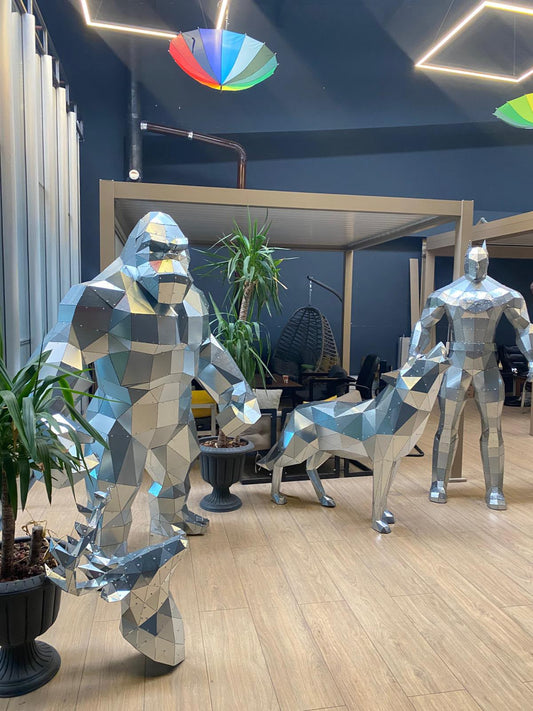 Showroom with three finished low poly metal sculptures side by side: a gorilla, a wolf and a standing figure